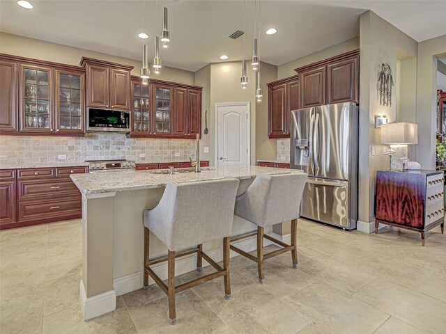 515 Sawgrass Bridge Rd, Venice, FL 34292 - kitchen featuring appliances with stainless steel finishes, backsplash, a kitchen island with sink, hanging light fixtures, and a kitchen breakfast bar
