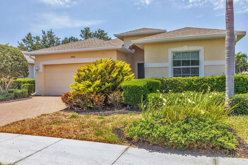 24849 Pennington Ter, Venice, FL 34293 - view of front of home featuring stucco siding, a garage, and decorative driveway