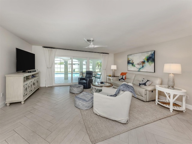 living area with ceiling fan and baseboards