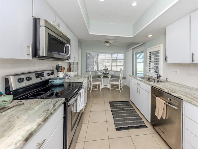 kitchen featuring stainless steel appliances, a sink, light tile patterned flooring, white cabinetry, and recessed lighting