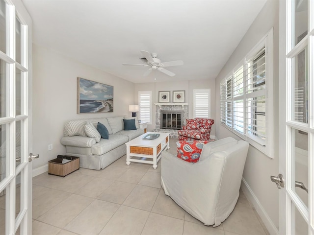 living room with french doors, light tile patterned floors, ceiling fan, and a glass covered fireplace