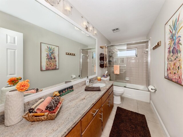 full bath featuring tile patterned flooring, toilet, vanity, shower / bath combination with glass door, and baseboards