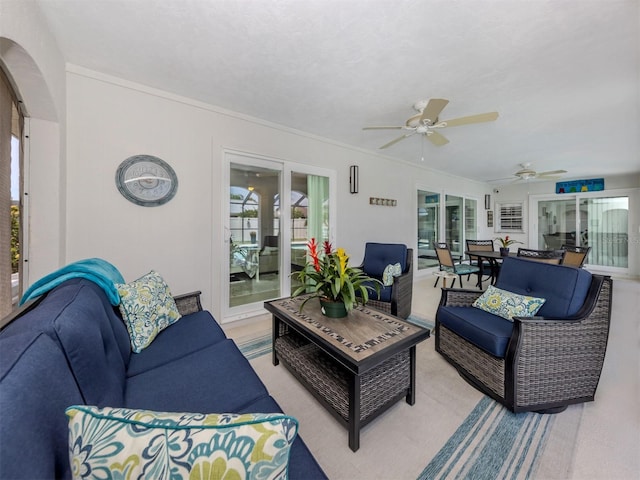 living area featuring plenty of natural light, ceiling fan, light carpet, arched walkways, and crown molding