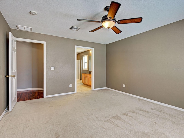 4103 Kinlock St, North Port, FL 34286 - unfurnished bedroom with light carpet, a ceiling fan, ensuite bath, and a textured ceiling