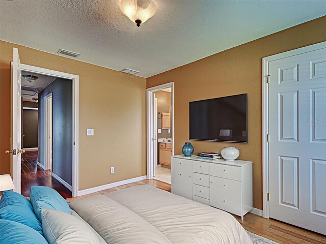 4103 Kinlock St, North Port, FL 34286 - bedroom with light wood-style flooring, ensuite bathroom, and a textured ceiling