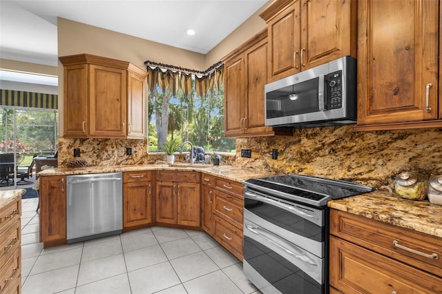 3950 Pepper Ln, North Port, FL 34287 - kitchen featuring stainless steel appliances, light stone countertops, brown cabinets, decorative backsplash, and light tile patterned flooring