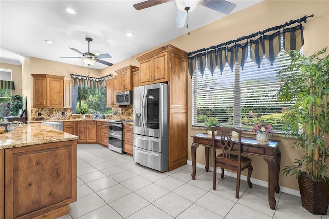 3950 Pepper Ln, North Port, FL 34287 - kitchen featuring stainless steel appliances, ceiling fan, backsplash, light stone counters, and brown cabinets