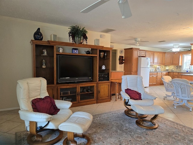 living room with ceiling fan, light tile patterned floors, and a textured ceiling