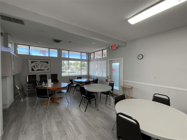 dining area featuring light wood-style flooring, baseboards, and a textured ceiling