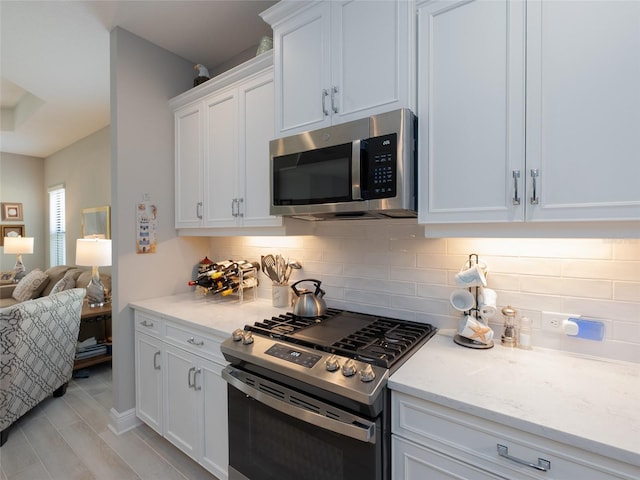 249 Tracino Ter, Nokomis, FL 34275 - kitchen featuring stainless steel appliances, decorative backsplash, white cabinets, open floor plan, and light stone counters