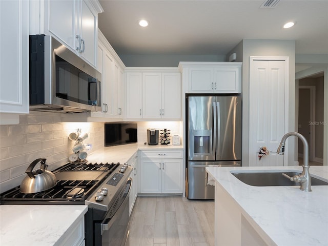 249 Tracino Ter, Nokomis, FL 34275 - kitchen with appliances with stainless steel finishes, a sink, white cabinetry, light stone countertops, and backsplash