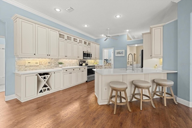 427 Autumn Chase Dr, Venice, FL 34292 - kitchen with stainless steel appliances, a sink, a peninsula, crown molding, and a breakfast bar area
