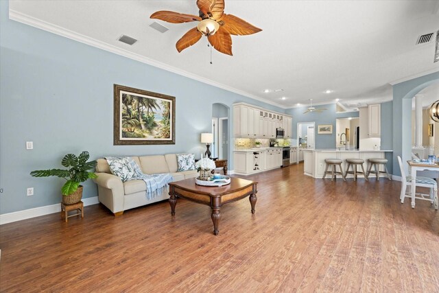 427 Autumn Chase Dr, Venice, FL 34292 - living area with arched walkways, ceiling fan, crown molding, light wood finished floors, and recessed lighting