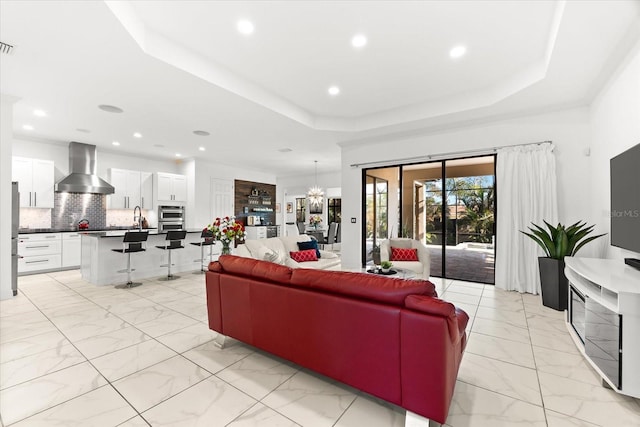 329 Myrtle Ave, Nokomis, FL 34275 - living room featuring light marble finish flooring, a raised ceiling, recessed lighting, and a chandelier