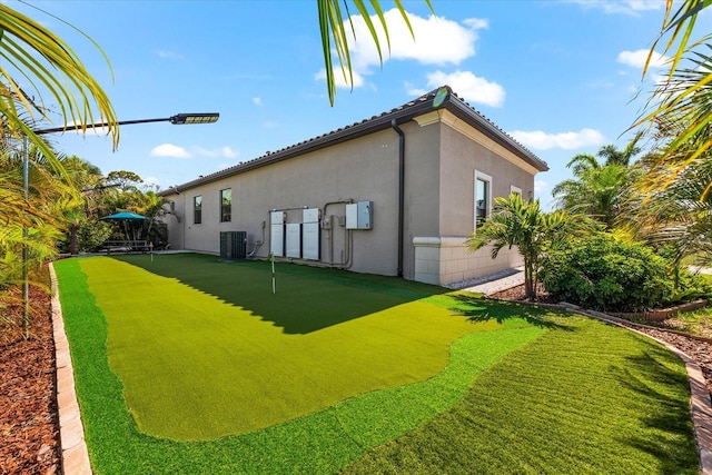 329 Myrtle Ave, Nokomis, FL 34275 - rear view of property with a putting green, central AC unit, and stucco siding