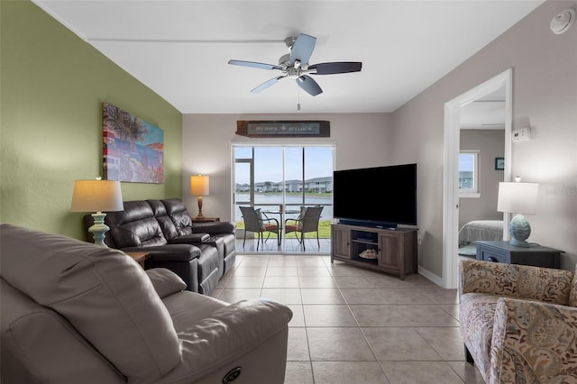 living area featuring a ceiling fan, light tile patterned floors, and baseboards