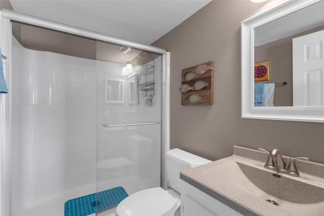 full bathroom featuring a stall shower, toilet, and vanity