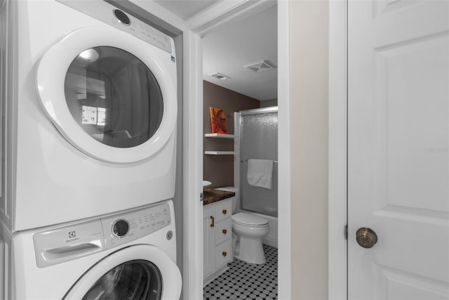 washroom with estacked washer and dryer and tile patterned floors