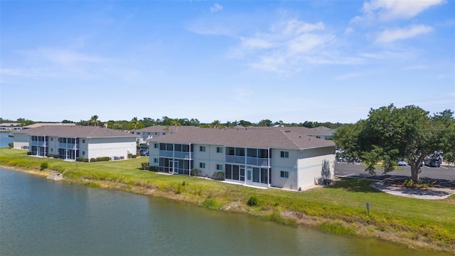 rear view of house with a water view and a yard