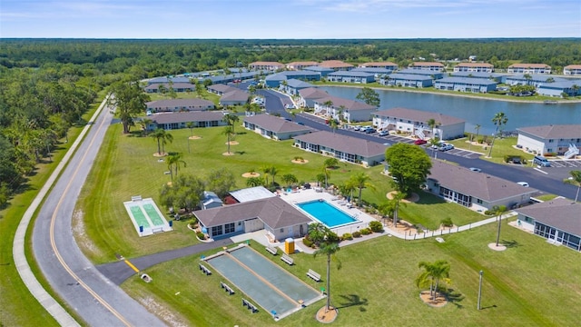 aerial view of property and surrounding area with a pool and a heavily wooded area