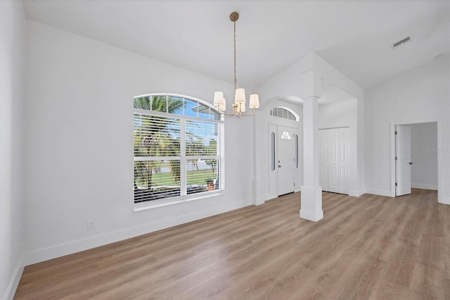 unfurnished dining area featuring a chandelier, lofted ceiling, wood finished floors, and baseboards