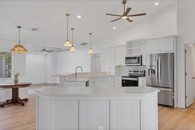 kitchen featuring stainless steel appliances, a ceiling fan, light wood-type flooring, light countertops, and lofted ceiling