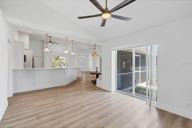 unfurnished living room with a ceiling fan, light wood-type flooring, a sink, and high vaulted ceiling