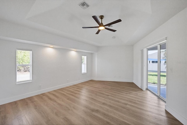 spare room with healthy amount of natural light, ceiling fan, wood finished floors, and baseboards