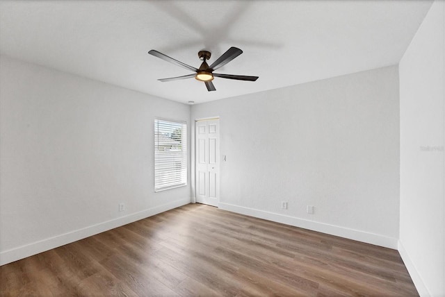 empty room with baseboards, wood finished floors, and ceiling fan