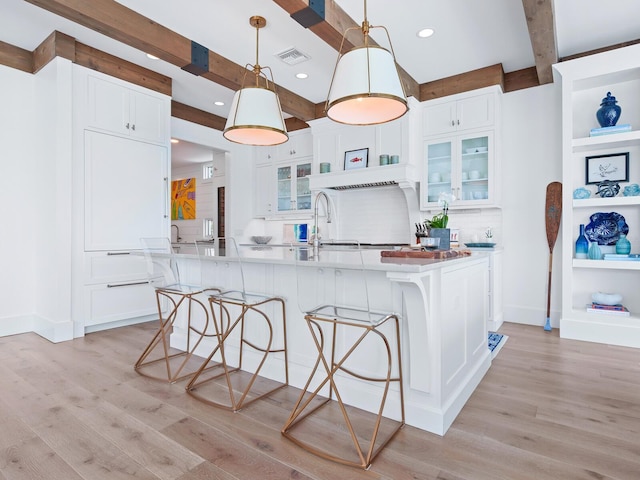 3516 Casey Key Rd, Nokomis, FL 34275 - kitchen featuring light wood-type flooring, backsplash, a kitchen breakfast bar, white cabinets, and beam ceiling