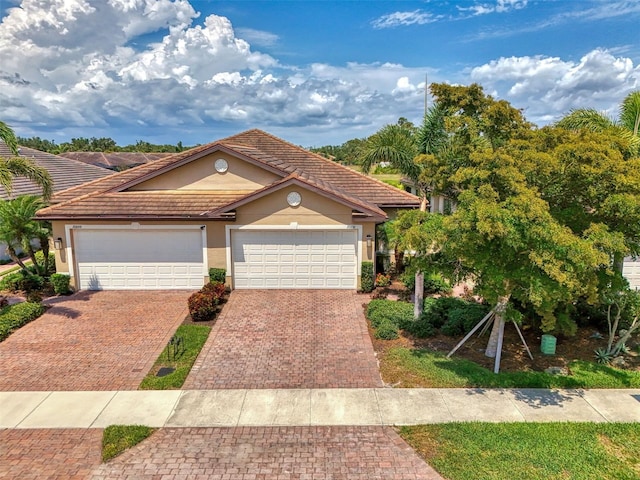 20636 Swallowtail Ct, Venice, FL 34293 - view of front of house featuring stucco siding, decorative driveway, a garage, and a tiled roof