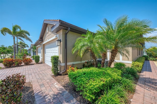 20636 Swallowtail Ct, Venice, FL 34293 - view of side of property featuring stucco siding, a garage, and driveway