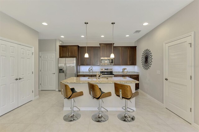 20636 Swallowtail Ct, Venice, FL 34293 - kitchen with appliances with stainless steel finishes, a sink, dark brown cabinets, a center island with sink, and a breakfast bar
