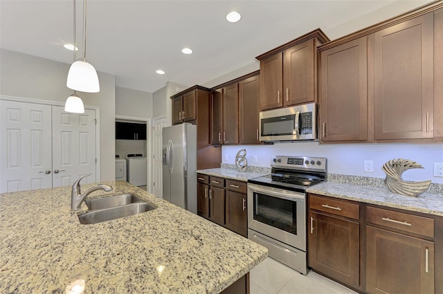 20636 Swallowtail Ct, Venice, FL 34293 - kitchen featuring stainless steel appliances, a sink, washer and dryer, light stone counters, and recessed lighting