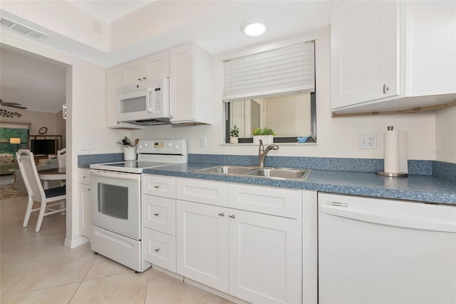 6796 Gasparilla Pines Blvd Unit 18, Englewood, FL 34224 - kitchen with white appliances, a sink, light tile patterned floors, dark countertops, and white cabinetry