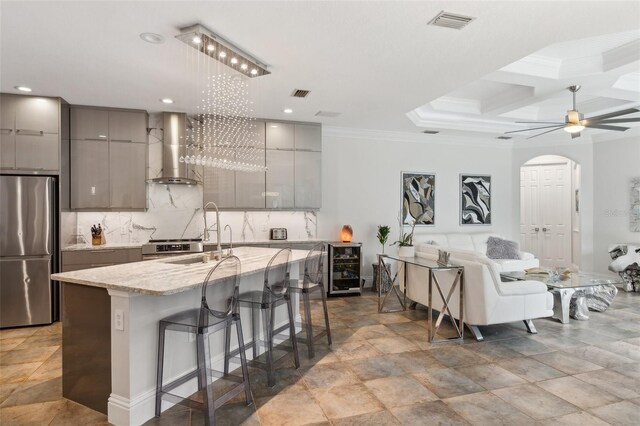 5850 Saddle Oak Trl, Sarasota, FL 34241 - kitchen featuring wall chimney range hood, appliances with stainless steel finishes, gray cabinetry, wine cooler, and coffered ceiling