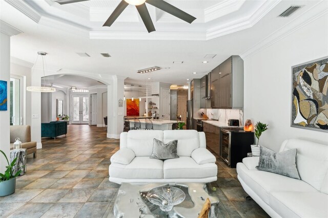 5850 Saddle Oak Trl, Sarasota, FL 34241 - living room with arched walkways, ornamental molding, a tray ceiling, a ceiling fan, and light stone finish flooring