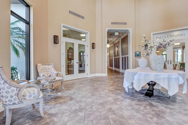10808 Tarflower Dr Unit 102, Venice, FL 34293 - entrance foyer featuring a towering ceiling, french doors, stone finish flooring, healthy amount of natural light, and baseboards