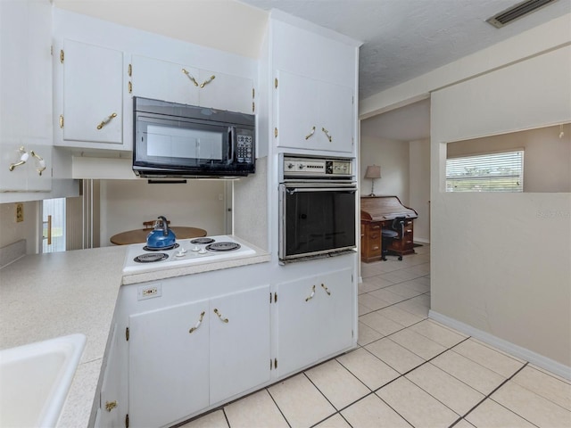 4192 Tarpon Rd, Venice, FL 34293 - kitchen with wall oven, black microwave, light tile patterned floors, a sink, and light countertops