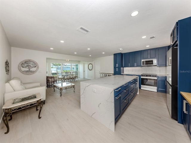 832 Whitecap Cir Unit 5, Venice, FL 34285 - kitchen with stainless steel appliances, a kitchen island, blue cabinets, light stone countertops, and recessed lighting