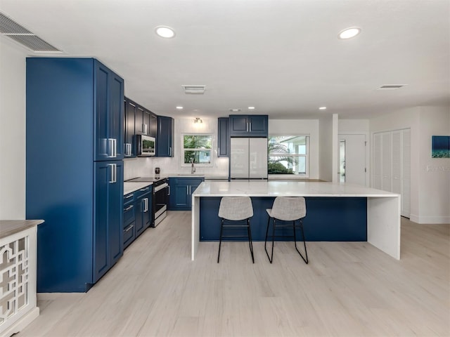 832 Whitecap Cir Unit 5, Venice, FL 34285 - kitchen with stainless steel appliances, a kitchen bar, recessed lighting, a kitchen island, and blue cabinets