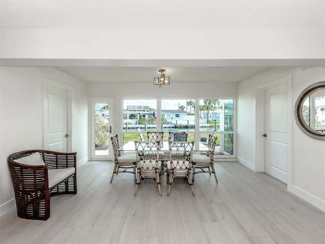 832 Whitecap Cir Unit 5, Venice, FL 34285 - dining room with baseboards, light wood-style floors, and a chandelier