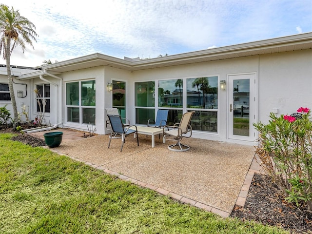 832 Whitecap Cir Unit 5, Venice, FL 34285 - rear view of property featuring stucco siding, a patio, and a yard