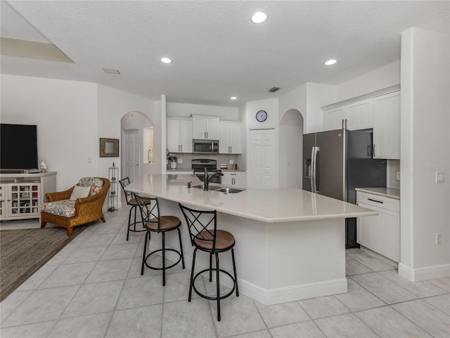463 Park Trace Blvd, Osprey, FL 34229 - kitchen featuring stainless steel appliances, a sink, arched walkways, light tile patterned flooring, and a kitchen bar