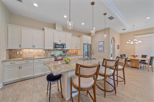 9220 43rd Ter W, Bradenton, FL 34209 - kitchen with stainless steel appliances, a sink, decorative backsplash, white cabinetry, and an island with sink