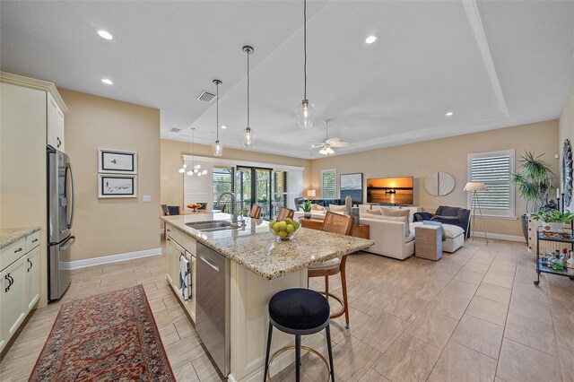 9220 43rd Ter W, Bradenton, FL 34209 - kitchen with a sink, appliances with stainless steel finishes, a breakfast bar, a tray ceiling, and a center island with sink
