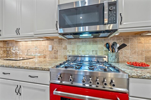 9220 43rd Ter W, Bradenton, FL 34209 - kitchen with stainless steel appliances, white cabinets, tasteful backsplash, and light stone counters