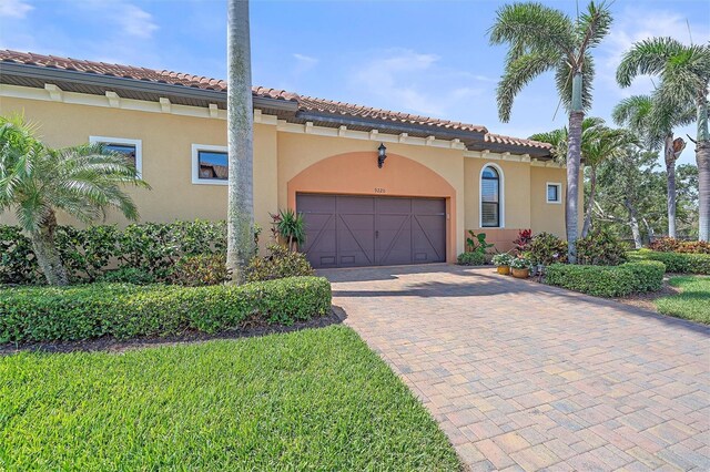 9220 43rd Ter W, Bradenton, FL 34209 - mediterranean / spanish-style home featuring an attached garage, a tile roof, decorative driveway, and stucco siding