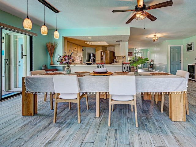 5832 Monroe Rd, Venice, FL 34293 - dining space featuring a textured ceiling, light wood-style flooring, a ceiling fan, and wine cooler