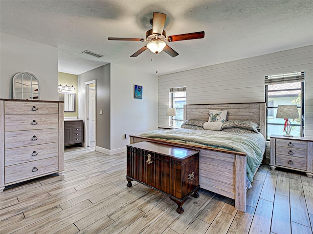 5832 Monroe Rd, Venice, FL 34293 - bedroom featuring light wood-style flooring, a textured ceiling, multiple windows, baseboards, and a ceiling fan